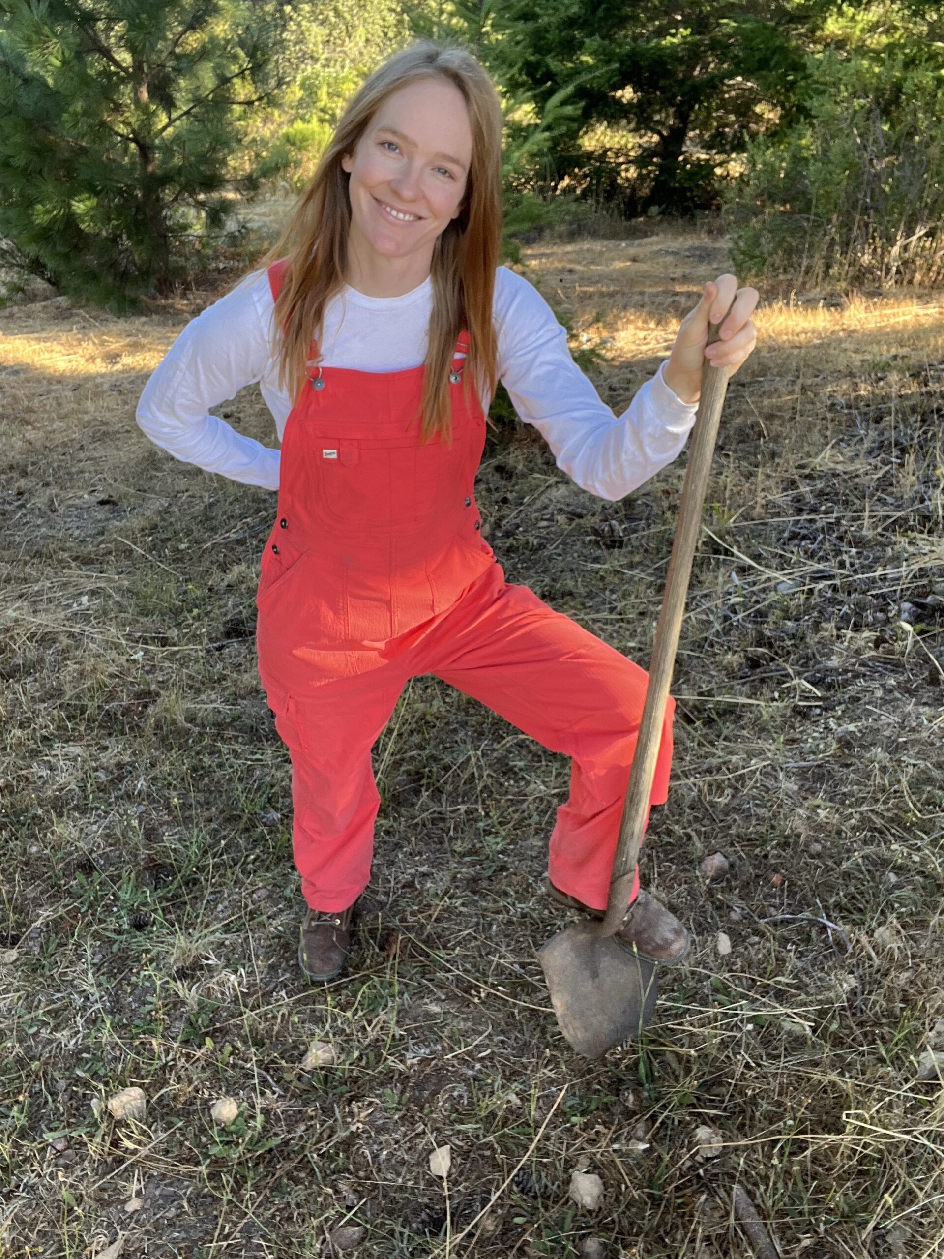 Cece standing on a scenic Sonoma County hill with a shovel in hand, ready to help with projects.